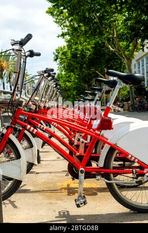 Beaucoup de vélos rouges - les vélos de ville sont soigneusement alignés et prêts à la location. Image montrant les détails et principalement de couleur rouge. Banque D'Images
