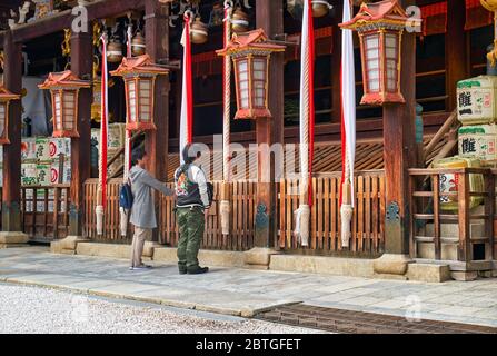 KYOTO, JAPON - 17 OCTOBRE 2019 : les adorateurs devant le sanctuaire principal (shaden) du sanctuaire Kitano Tenmangu pour sonner la cloche au-dessus des offrandes Banque D'Images