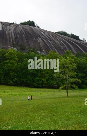 Les randonneurs traversent un champ sous le dôme géant en granit qui est le nom du parc national de Stone Mountain en Caroline du Nord. Banque D'Images