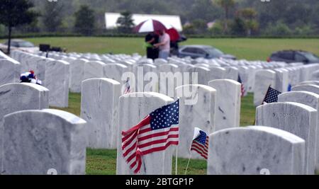Les drapeaux américains sont vus par une pierre d'honneur le jour du souvenir au cimetière national de Cape Canaveral. Banque D'Images