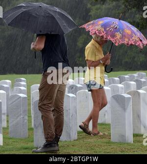 Les gens tiennent des parasols lorsqu'ils visitent le cimetière national du Cap Canaveral sous la pluie le jour du souvenir. Banque D'Images