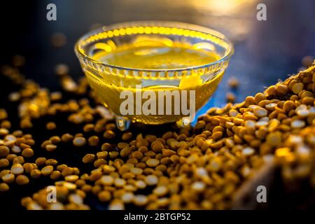 Pâte de pois chiches fraîchement bouillie dans un bol en verre sur une surface noire avec quelques lentilles de pois chiches crues. Banque D'Images