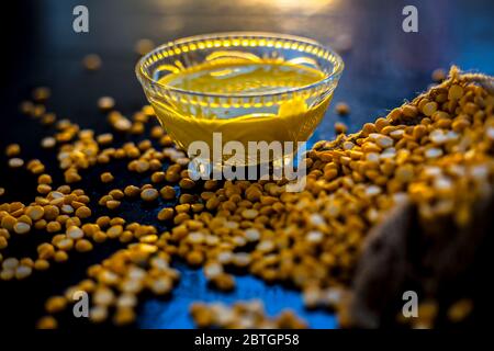 Pâte de pois chiches fraîchement bouillie dans un bol en verre sur une surface noire avec quelques lentilles de pois chiches crues. Banque D'Images