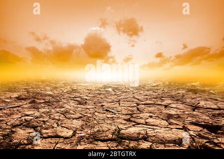 Sol fissuré en été avec le coucher du soleil ou des fissures du sol séché en saison aride sur fond de ciel orange. Réchauffement climatique Banque D'Images