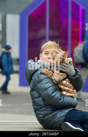 Mignon hipster garçon marche avec son drôle de terrier. Petit chien avec jeune gars passer une journée à jouer en plein air et à s'amuser. Portrait de style de vie. L'amour entre animal et propriétaire. Banque D'Images