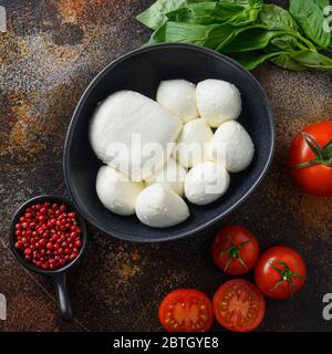 Tomates cerises fraîches, feuilles de basilic, mozzarella et huile d'olive sur fond métallique rustique ancien. Ingrédients de la salade Caprese. Mise au point sélective haut v Banque D'Images