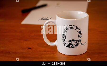 Symbole QAnon sur une tasse blanche sur un bureau en bois, théorie du complot, concept d'état profond Banque D'Images