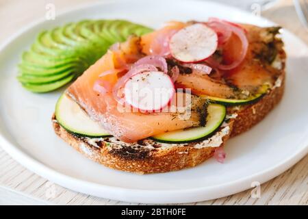 Toast au saumon avec avocat et légumes dans le café moderne. Café chic et concept moderne de collations santé. À emporter, élément de menu livraison Banque D'Images