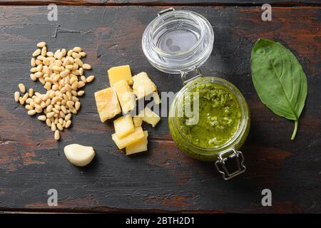 Pesto alla Genovese maison dans un pot en verre avec ingrédients parmesan basilic pignons de pin. Sur les planches de table en bois sombre vue de dessus vintage. Banque D'Images