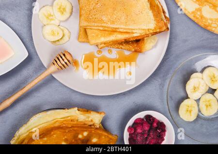 Crêpes avec baies et miel pour le petit déjeuner sur table rustique grise Banque D'Images