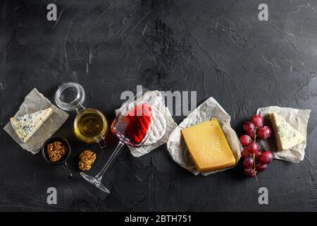 Assortiment de fromages, antipasti Camembert un verre de vin rouge, miel, noix et épices, sur fond noir ardoise de pierre vue du dessus. Espace libre pour le texte Banque D'Images