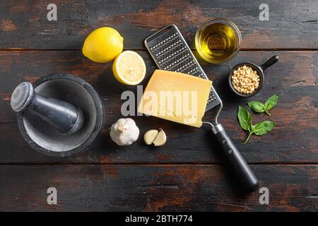 Ingrédients de cuisine italienne pour la sauce pesto basilic, huile d'olive, parmesan, ail, pignons. Sur table rustique sombre vue sur personne. Banque D'Images