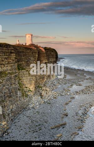 Phare de Nash point, sud du pays de Galles, au coucher du soleil. Le phare est situé au sommet de falaises abruptes, surplombant le canal de Bristol Banque D'Images