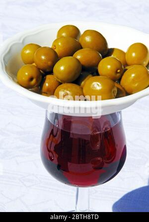 Verre de vin rouge avec plat d'olives vertes sur le dessus pour garder les mouches hors (tapas modernes provient du mot tapa signifiant à couvrir), Espagne. Banque D'Images