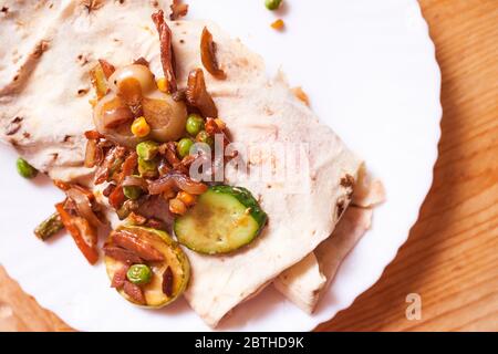 shaverma maison. Saucisses, concombres, légumes grillés sont sur une pita Banque D'Images