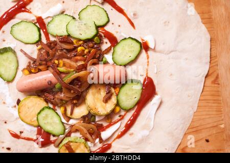 ingrédients pour la shaverma maison. Saucisses, concombres, légumes grillés sont sur une pita Banque D'Images