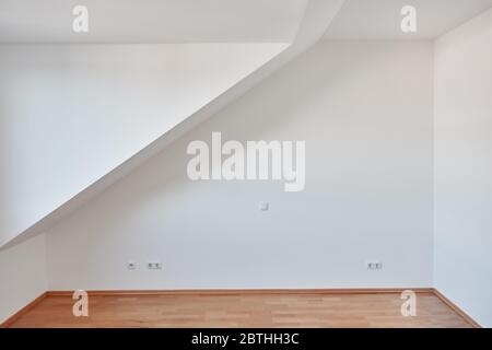 Mur blanc avec plafonds inclinés dans la chambre vide avec parquet de l'appartement loft à la maison Banque D'Images