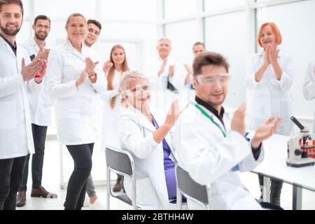 groupe de jeunes scientifiques félicitant leur collègue d'applaudissements Banque D'Images