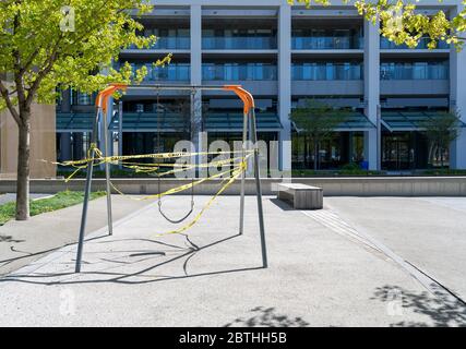 Aire de jeux fermée pour enfants avec siège pivotant enveloppée de ruban d'avertissement jaune pendant la pandémie mondiale du coronavirus COVID-19 Banque D'Images