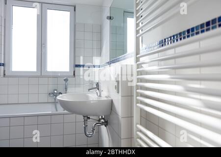 Lavabo en céramique blanche dans la salle de bains lumineuse avec radiateur et fenêtre Banque D'Images