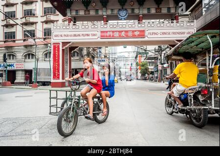 Deux jeunes filles philippines locales traversent la jonction animée de l'Arc d'amitié philippin chinois dans le quartier de Binondo Chinatown à Manille Philippines. Banque D'Images