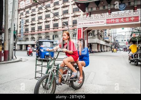 Deux jeunes filles philippines locales traversent la jonction animée de l'Arc d'amitié philippin chinois dans le quartier de Binondo Chinatown à Manille Philippines. Banque D'Images