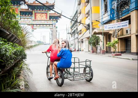 Deux jeunes filles philippines locales traversent la jonction animée de l'Arc d'amitié philippin chinois dans le quartier de Binondo Chinatown à Manille Philippines. Banque D'Images