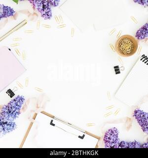 Composition d'espace de copie avec bloc-notes, bloc-notes, fleurs lilas et accessoires isolés sur fond blanc. Flat lay, vue de dessus Banque D'Images