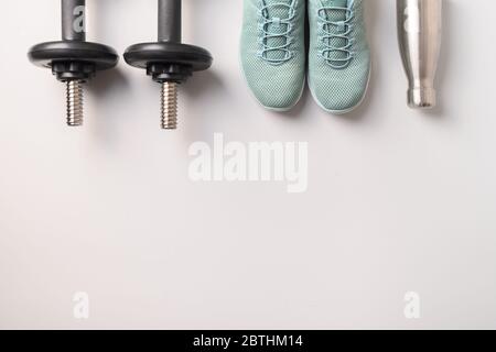 Équipement de sport et de fitness, haltères, chaussures, bouteille d'eau sur fond gris. Afficher depuis le haut, espace pour votre texte. Banque D'Images