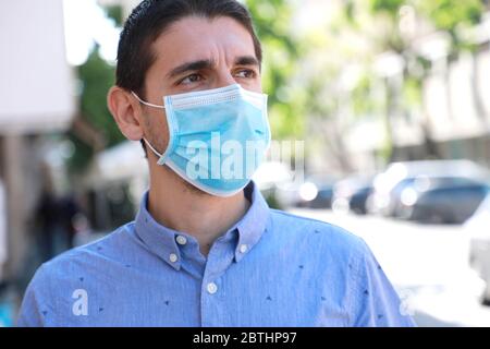 COVID-19 coronavirus pandémique Homme dans la rue de la ville portant un masque chirurgical sur le visage pour la propagation de la maladie du coronavirus 2019. Portrait de l'homme avec ma visage Banque D'Images