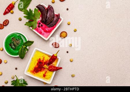 Hummus, nourriture végétalienne (végétarienne) saine. Trois types variés : classique, menthe et betterave. Haricots secs édamame, morceaux de pain pita, épices. Béton de pierre Banque D'Images