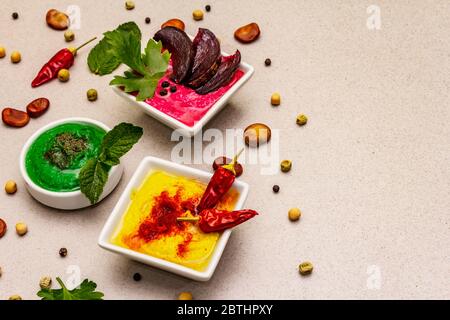 Hummus, nourriture végétalienne (végétarienne) saine. Trois types variés : classique, menthe et betterave. Haricots secs édamame, morceaux de pain pita, épices. Béton de pierre Banque D'Images