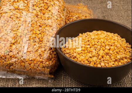 Petits pois jaunes dans un sac de cellophane et céréales dans un bol en céramique sur fond de toile de jute à texture grossière. Céréales traditionnelles pour faire des soupes et Banque D'Images