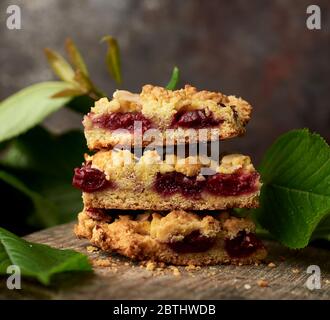 pile de morceaux carrés de tarte aux crumbles avec cerise sur un plateau en bois, délicieux dessert Banque D'Images