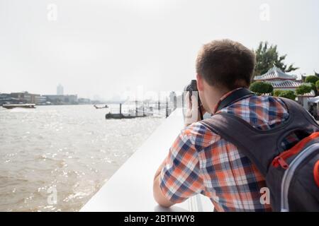 Un jeune voyageur ou un photographe visite la ville en faisant une photo de la rivière à Bangkok. Photographie et tourisme. Tourist prend une photo de la ville Banque D'Images