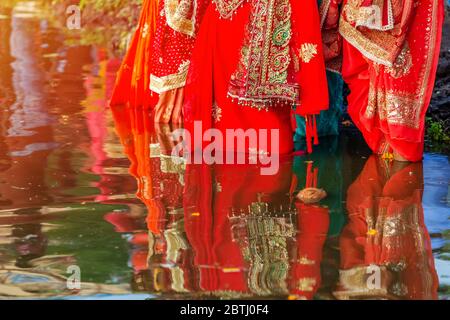 Femme hindoue népalaise debout dans l'eau avec des offrandes au crépuscule pour prier en buvant le soleil pendant le festival Chhath Puja Banque D'Images