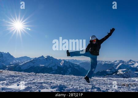 Fille avec des lunettes et un casque est en plein air en hiver. Ciel bleu et soleil éclatant au sommet des montagnes en Suisse. Concept. Banque D'Images