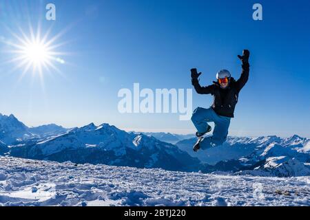 Fille avec des lunettes et un casque est en plein air en hiver. Ciel bleu et soleil éclatant au sommet des montagnes en Suisse. Concept. Banque D'Images