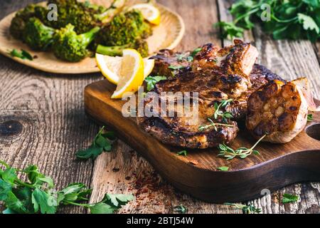 Steak de bœuf aux yeux avec broccolini, herbes et ail sur une table en bois rustique Banque D'Images