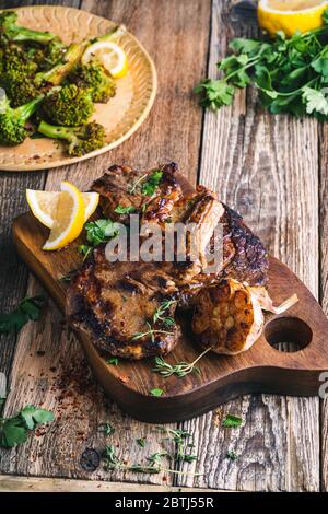 Steak de bœuf aux yeux avec broccolini, herbes et ail sur une table en bois rustique Banque D'Images