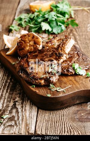 Bifteck de côtes aux herbes et à l'ail sur une table en bois rustique Banque D'Images