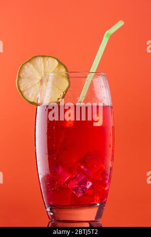 verre de boisson froide rouge sur fond orange dans un verre agréable et avec une paille prête à boire Banque D'Images