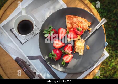 Table de petit déjeuner du week-end vue d'en haut. Gâteau rhubarbe avec fraises et une tasse de café Banque D'Images