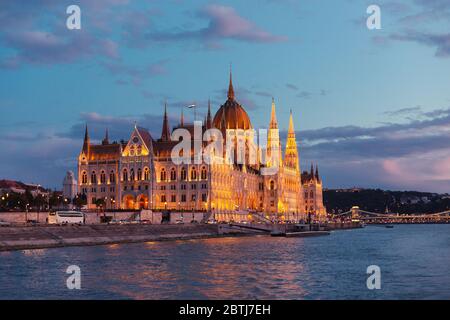 Le Parlement de Budapest s'est illuminé au coucher du soleil, vu d'une promenade en bateau sur le Danube Banque D'Images