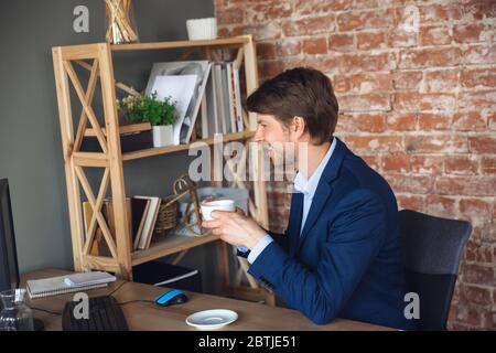 Café inspiré, tâches de lecture. Le jeune homme, le gérant, retourne au travail dans son bureau après la quarantaine, se sent heureux et inspiré. Revenir à la vie normale. Concept affaires, finances, émotions. Banque D'Images