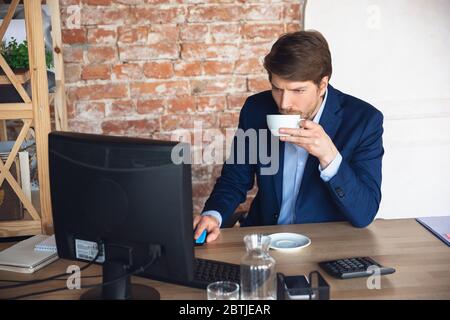 Café inspiré, tâches de lecture. Le jeune homme, le gérant, retourne au travail dans son bureau après la quarantaine, se sent heureux et inspiré. Revenir à la vie normale. Concept affaires, finances, émotions. Banque D'Images