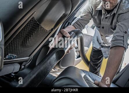 Garder la voiture propre à l'intérieur. Les hommes du Caucase nettoyant sa voiture en passant l'aspirateur à l'intérieur. Industrie du transport. Entretien du véhicule. Banque D'Images