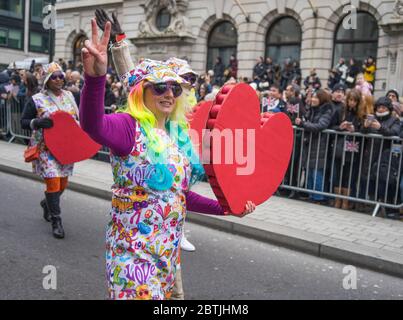 Défilé du nouvel an à Londres 2020. Dame aux cheveux arc-en-ciel tenant un grand coeur rouge. Banque D'Images