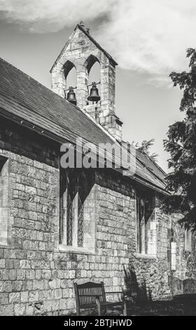 L'église de campagne de Saint Everilda à Poppleton près de York. Un banc est placé contre un mur et un clocher est au-dessus. Banque D'Images