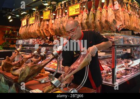 Un homme qui coupe le jambon de jamon au marché de barcelone. Jamón est une sorte de jambon sec-fumé produit en Espagne. Banque D'Images